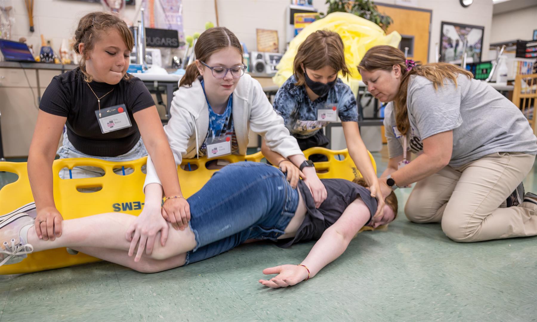 A group of students prepares to flip someone onto a spine board